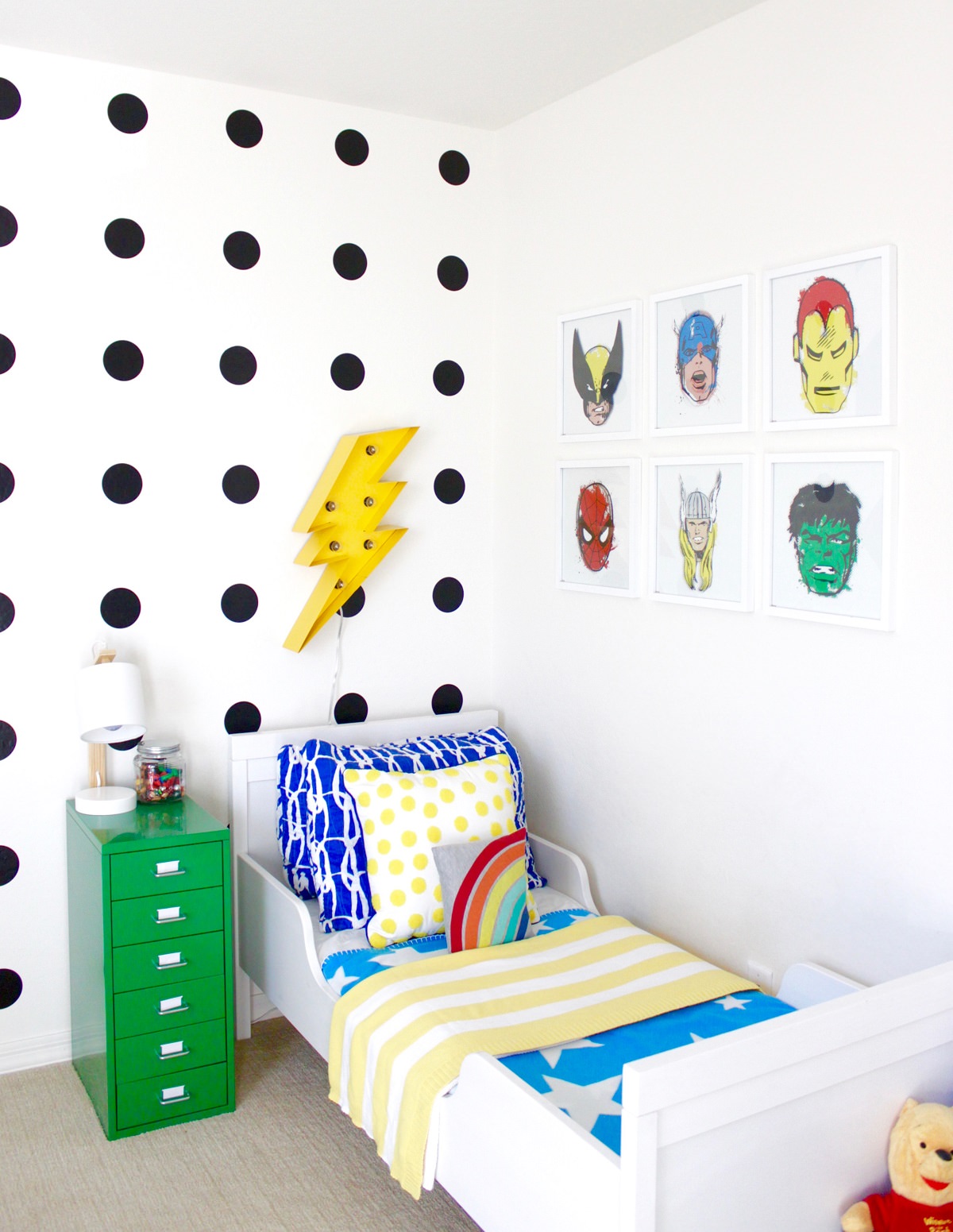 دکوراسیون اتاق خواب کودک پسر شیک با تخت سفید که روی دیوار آن کاغذ دیواری نقطه چین و تابلوهای هالک و مرد عنکبوتی نصب شده است